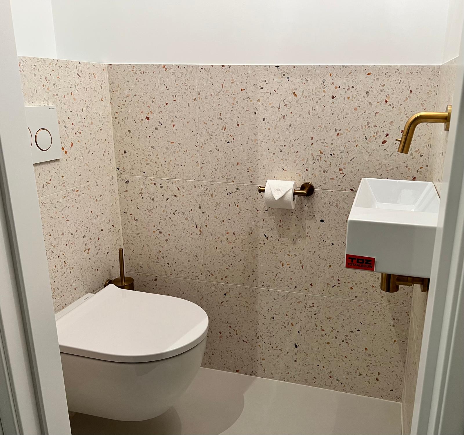 Toilet met terrazzo tegels en messing kranen